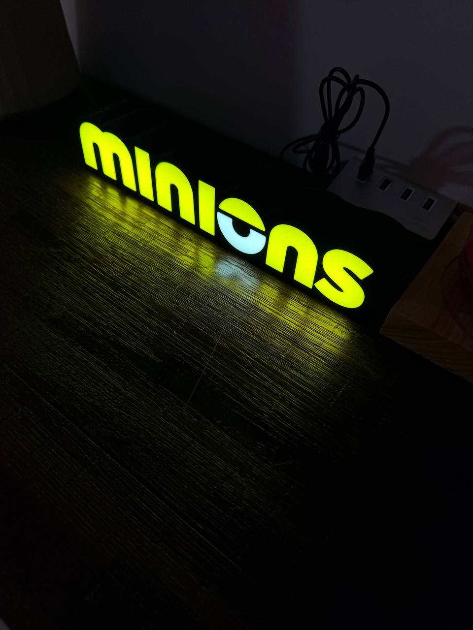 Minions LED sign glowing on desk — angled view