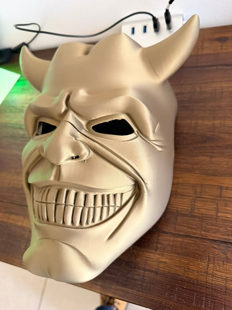 The Grabber horror mask from The Black Phone - front three-quarter view showing gold finish and devil horns