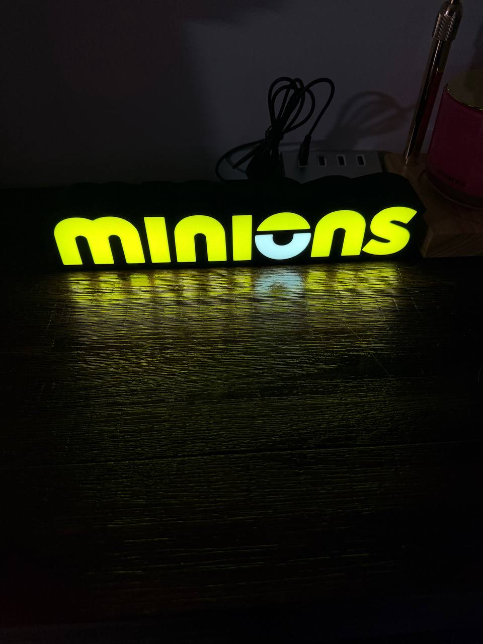 Minions eye logo LED sign illuminated, close-up front view