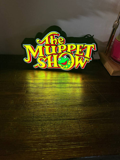 The Muppet Show LED light-up sign glowing on wooden desk — front view