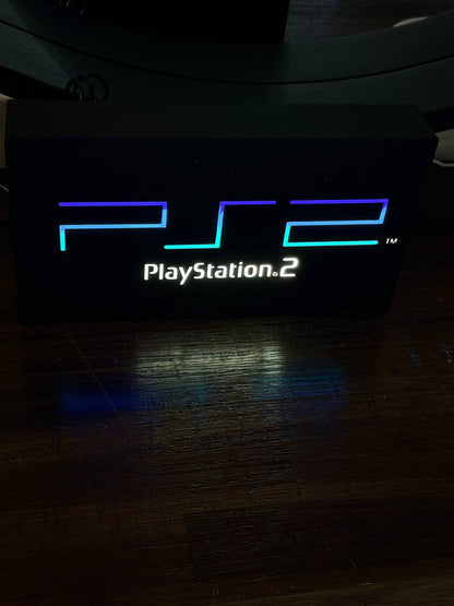 Sony PlayStation 2 LED light-up sign (full logo) glowing in a dark room — original PS2 colours